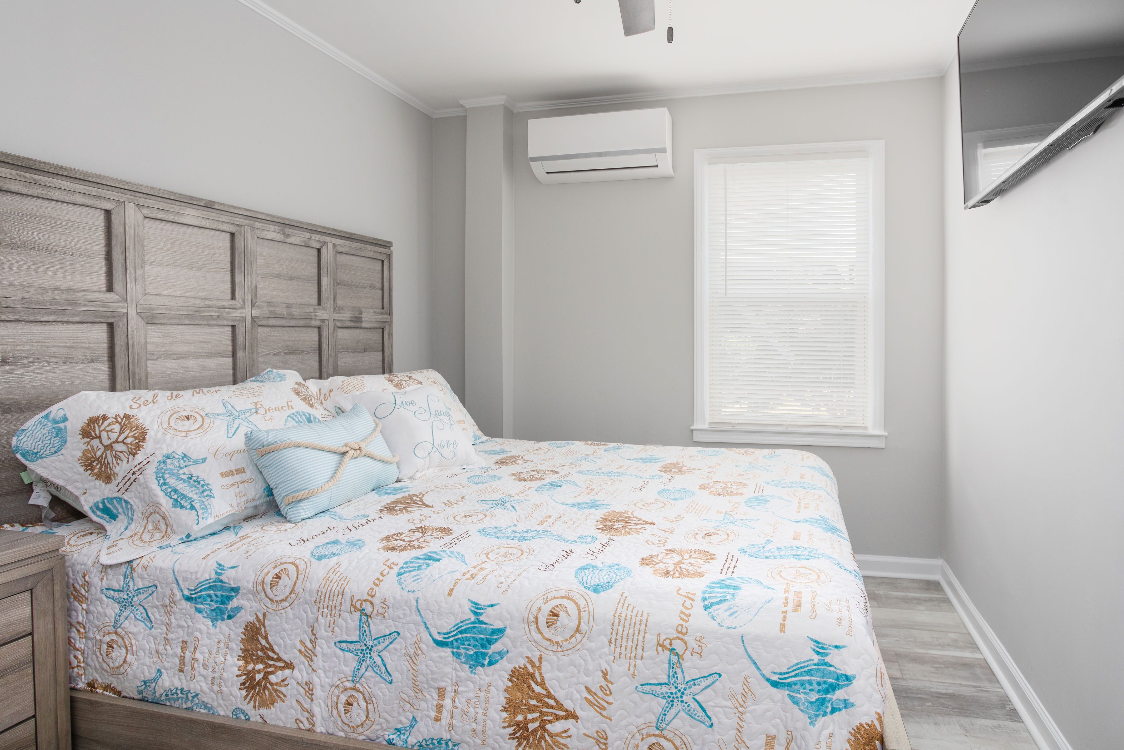 Un dormitorio con cama, mesita de noche, ventana con persianas y aire acondicionado en la pared.