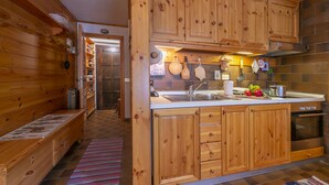 A wooden cabin interior with a kitchen area featuring wooden cabinets, a sink, and a stove. - Casa Cisi ski in-Ski out 20m, Livigno, Italy (Livigno)