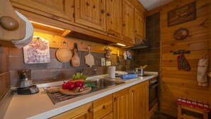 A kitchen with wooden cabinets, a sink, and various kitchen utensils. - Casa Cisi ski in-Ski out 20m, Livigno, Italy (Livigno)