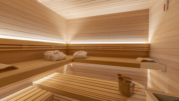 A sauna with wooden benches and benches, a wooden table, and a bucket with towels. - Menina, Livigno, Italy (Livigno)