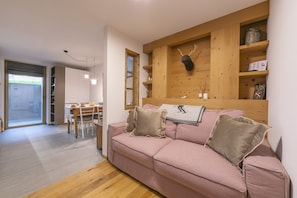 A living room with a pink sofa, wooden shelves, and a deer head decoration.