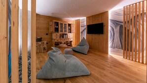 A room with wooden walls, a television mounted on the wall, a cabinet with drawers, and a sofa. - Menina, Livigno, Italy (Livigno)