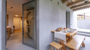 A modern kitchen with a wooden table and bench, a glass door leading to another room, and a view of the outside. - Menina, Livigno, Italy (Livigno)