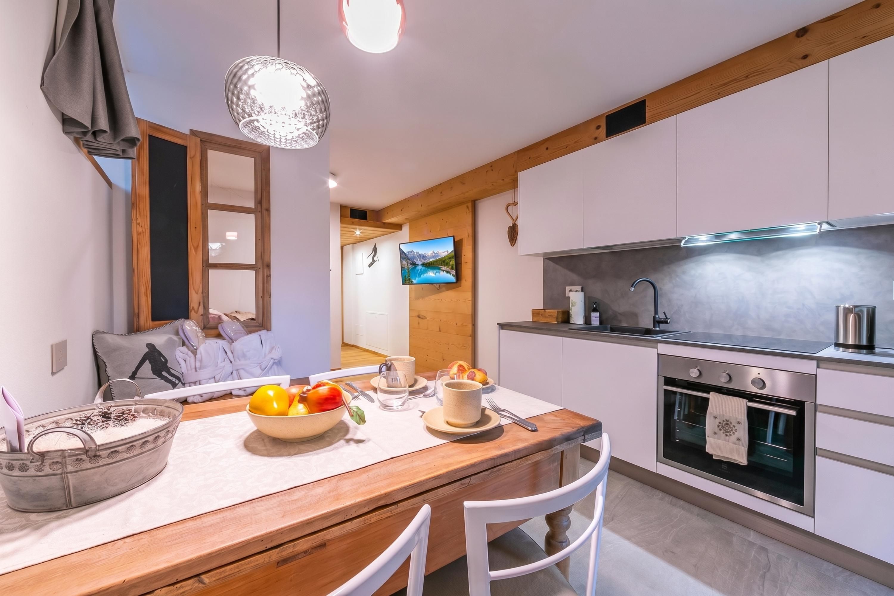 A modern kitchen with wooden cabinets, a built-in oven, and a dining area with a wooden table and chairs.