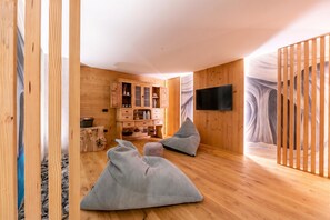 A modern interior with wooden walls, a flat-screen TV, and a seating area with bean bags.