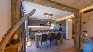 A modern kitchen with wooden beams, a dining area with four chairs, and a blue sofa. - Giulia, Livigno, Italy (Livigno)
