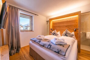 A hotel room with a bed, a window with curtains, a wooden headboard, and a view of buildings outside.