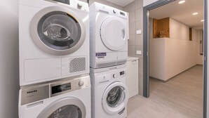 A laundry area with two stacked washing machines and a dryer.
