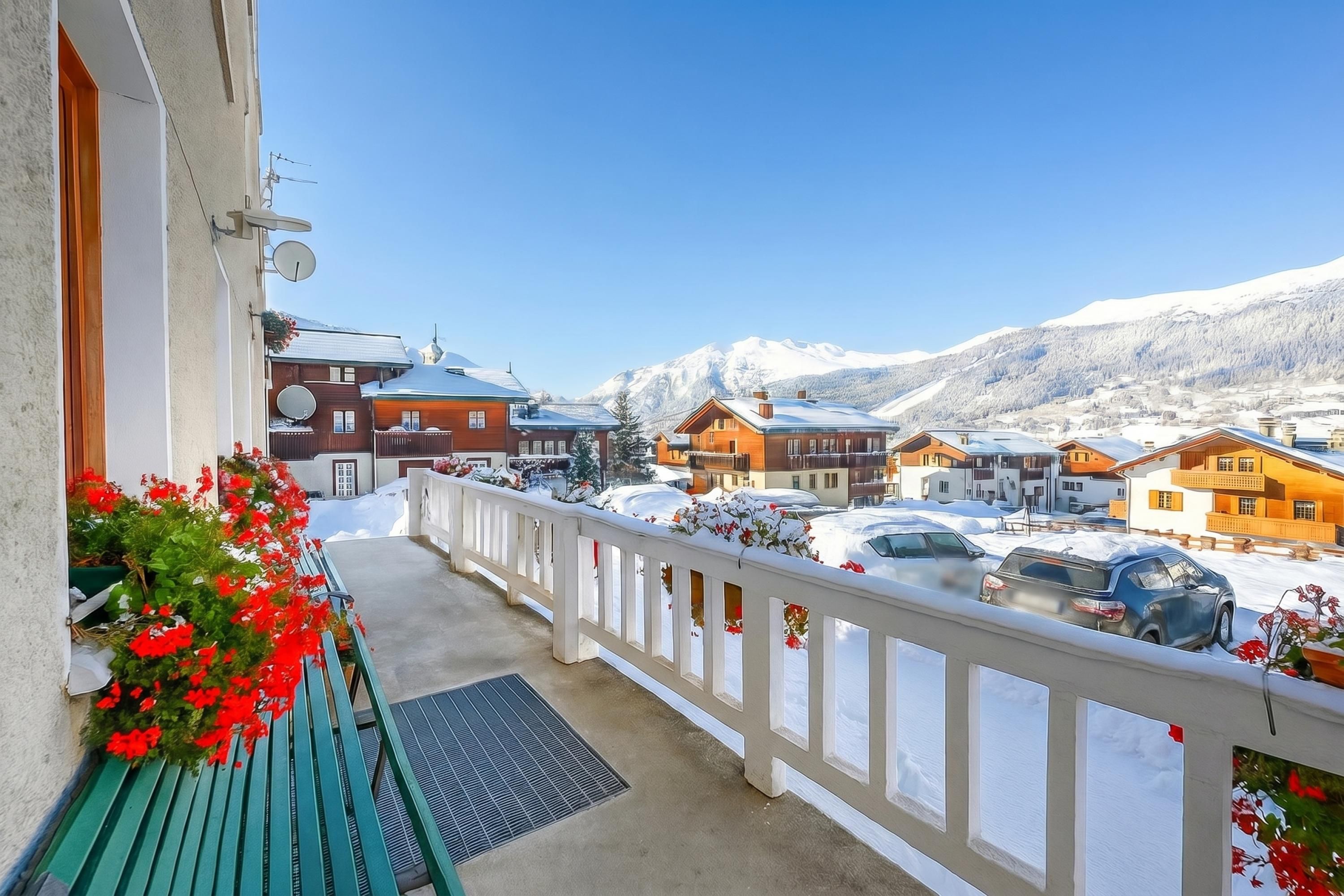 A balcony with a view of a snow-covered mountain and parked cars.