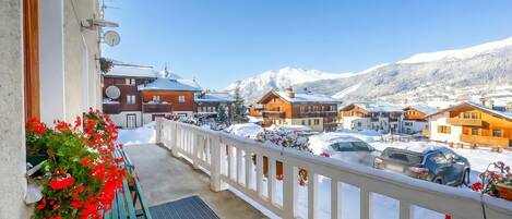 A balcony with a view of a snow-covered mountain and parked cars.