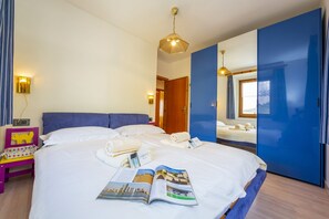 Habitación de hotel con una cama grande, una mesita de noche con lámpara, un espejo y vistas al exterior.