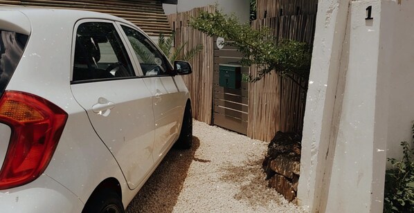 A white car parked in a driveway with a wooden fence and a gate.