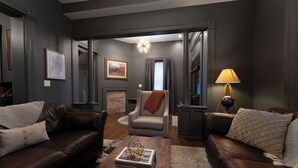 A modern living room with dark walls, leather sofas, a wooden coffee table, and a lamp.