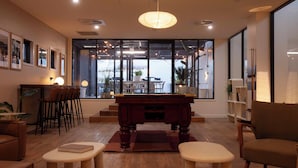 Una sala de estar moderna con una mesa de billar, asientos cómodos, ventanas amplias y vistas al exterior.