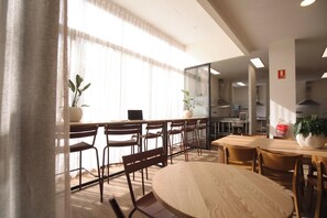A modern meeting room with a round table, wooden chairs, a laptop, and potted plants. - Little Drifter Canberra (Canberra)