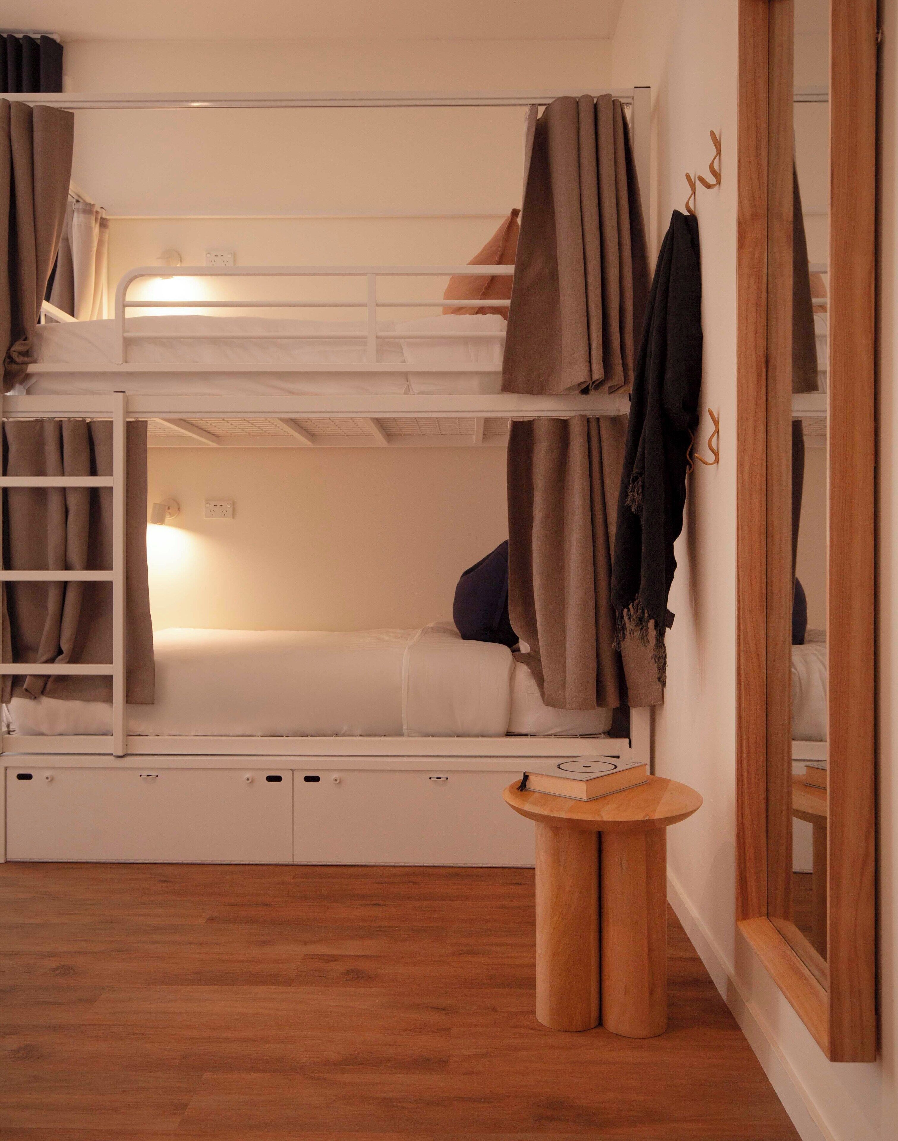 Dormitorio con literas, una pequeña mesa de madera y un espejo.