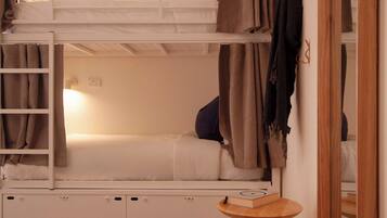 Dormitorio con literas, una pequeña mesa de madera y un espejo.