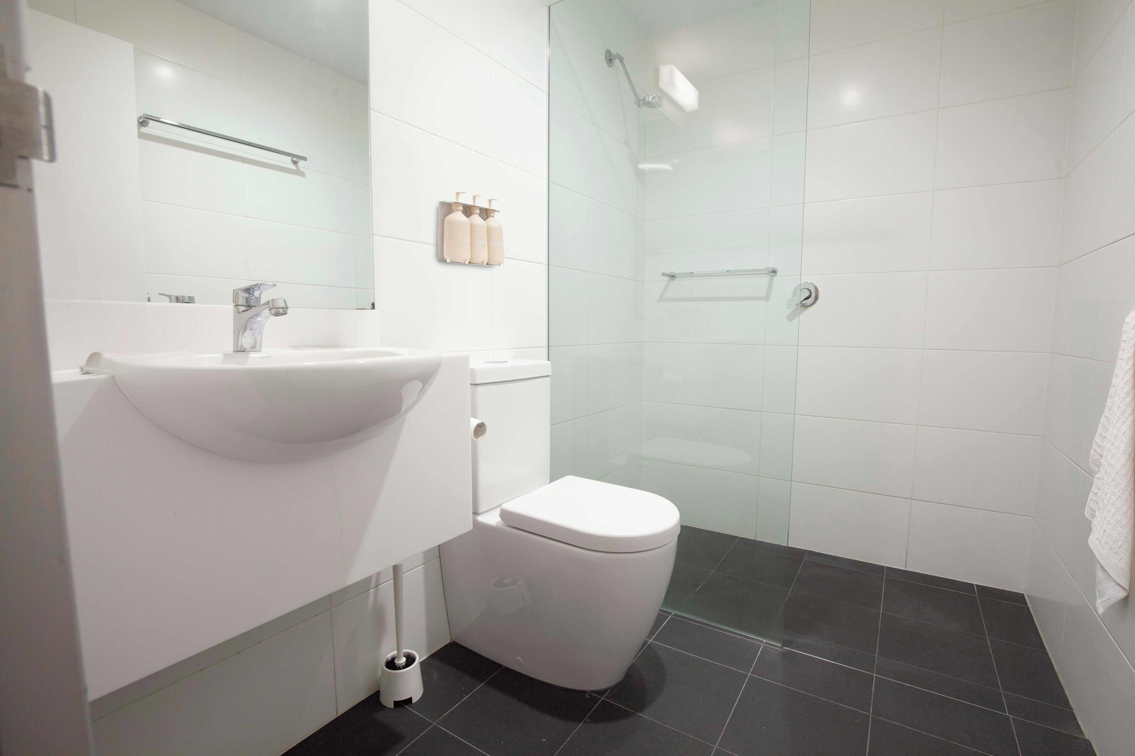 Un baño moderno con lavamanos blanco, inodoro y cabina de ducha de vidrio.
