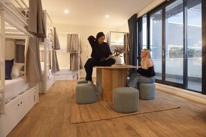 A modern room with bunk beds, a central table, and ottomans. - Little Drifter Canberra (Canberra)