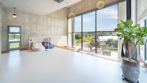 Een ruime kamer met grote ramen, een potplant en uitzicht op het omliggende landschap.