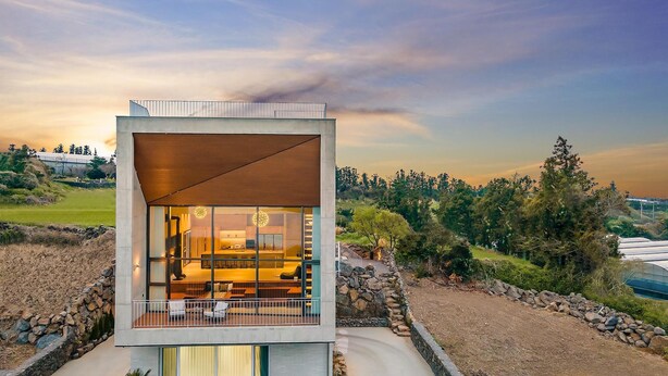 Een modern huis met een groot raam, een balkon en uitzicht op het omliggende landschap.