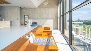 Een modern interieur met een lange houten bank, een witte bank en een vloerkleed met een patroon.