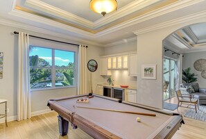 Una mesa de billar en una habitación bien iluminada, con vistas al exterior a través de un amplio ventanal.