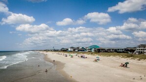 A beach with houses in the background and people on the sand. - Dog Friendly Cottage w/ Large Fenced in Backyard - Close to Beach (Oak Island)