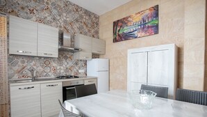 A modern kitchen with a dining area. It includes a stove, sink, cabinets, and a refrigerator.
