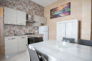 A modern kitchen with a dining area. It includes a stove, sink, cabinets, and a refrigerator. - Bea Apartment | 2 bedrooms house, wifi, a/c (Porto Cesareo)