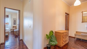 A hallway with wooden flooring, a potted plant, a wooden cabinet, and a bench. - Central Apartment Near the Beaches (Lagos)