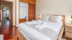 A hotel room with a large bed, wooden wardrobe, and a bathroom visible through an open door. - Central Apartment Near the Beaches (Lagos)
