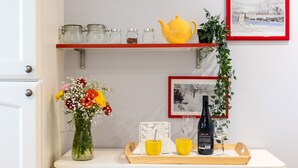 En køkkenbordplade med en vase med blomster, en gul tepotte og en vinflaske på et bakke.