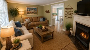 Una sala de estar con sofá, mesa de centro, chimenea y televisor.