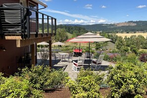 Une terrasse avec des sièges extérieurs, un espace barbecue couvert et une vue sur un paysage vallonné.