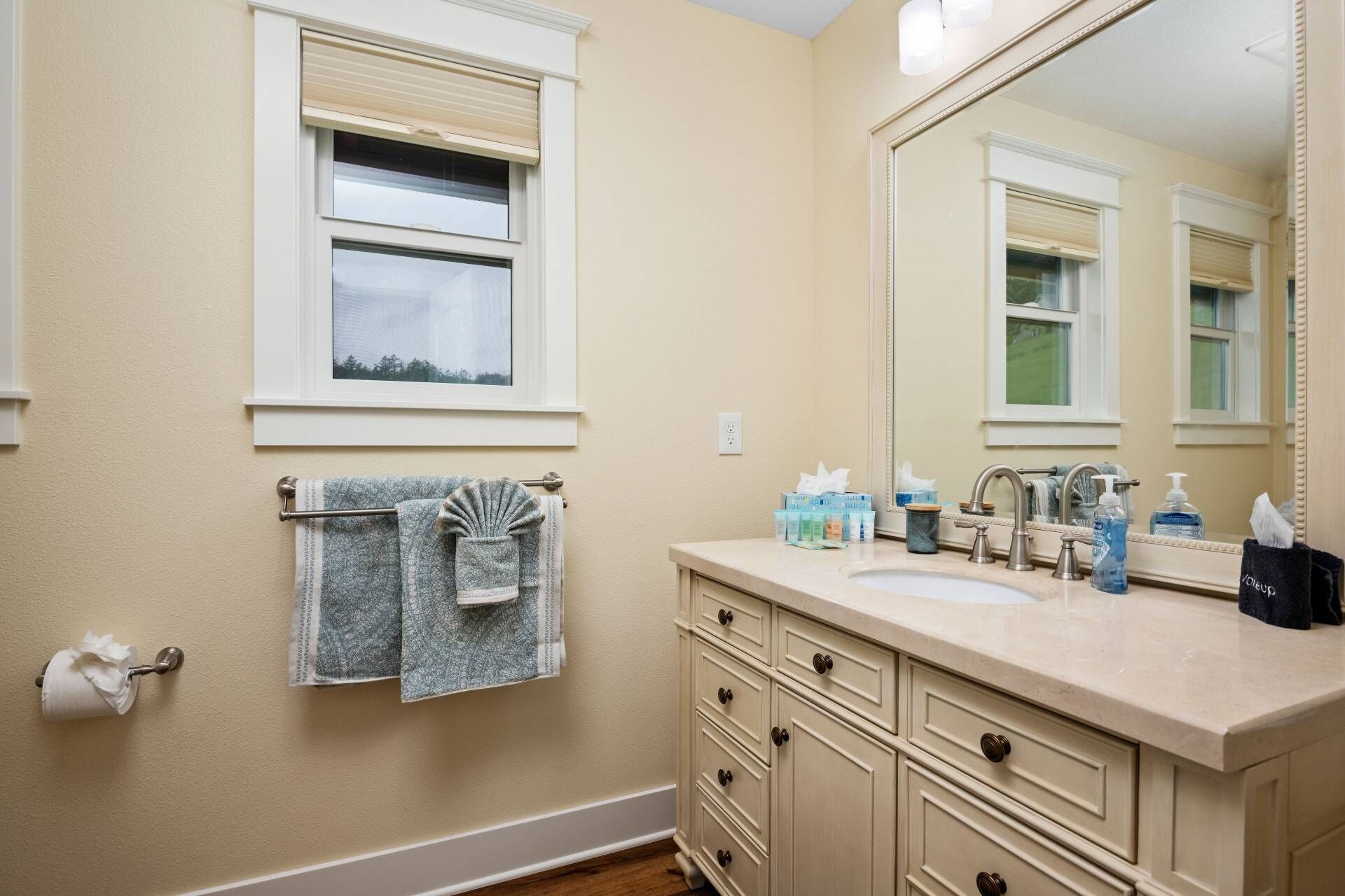 A bathroom with a sink, mirror, towel rack, and toiletries.