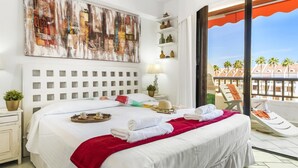 A hotel room with a large bed, a balcony with a view of palm trees, and a painting on the wall. - 231 Parque Santiago II, 2 bedrooms, 2 bathrooms, Wi-Fi, beach and pool (Arona)