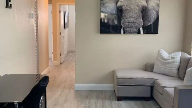 A living room with a beige sofa, a black table, and a wall-mounted elephant artwork.