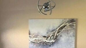 A dining area with a round table, two chairs, and a wall-mounted abstract painting.