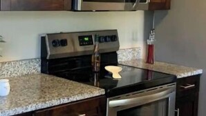A kitchen with wooden cabinets, a stainless steel microwave, an oven, and a granite countertop.