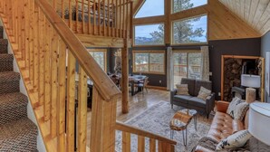 Ein geräumiges Loft mit hohen Decken, großen Fenstern, einer Holztreppe und einer gemütlichen Sitzecke mit Kamin.