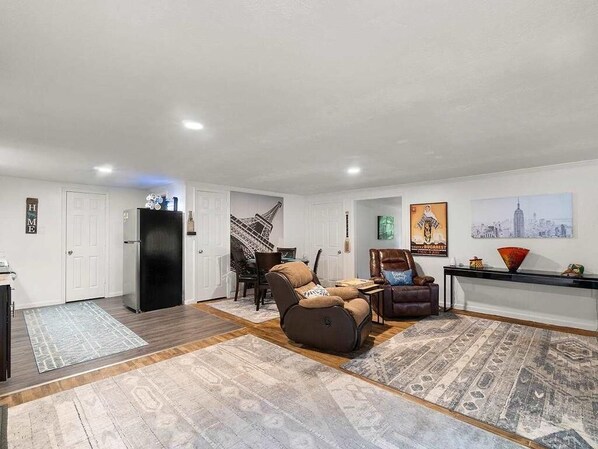 A spacious living area with a modern sofa, a dining table, and a kitchen area with a refrigerator.
