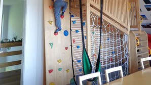 A child climbing a wooden climbing wall with various holds.