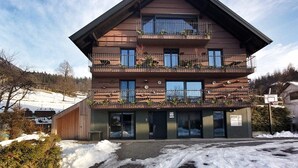A multi-story hotel with balconies, a wooden facade, and a snow-covered ground.