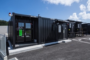Un bâtiment moderne à l’extérieur noir, doté d’une entrée en verre et d’une enseigne indiquant « The Yard ».