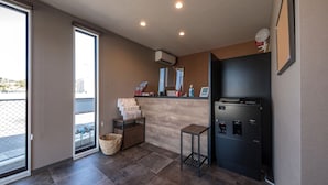 A modern bathroom with a large mirror, a sink, and a toilet. There is a window providing natural light and a view of the outside. - HOTEL R9 The Yard Uruma (Uruma)