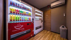 A vending machine with a variety of beverages and a coffee machine labeled "Good Coffee Smile." - HOTEL R9 The Yard Uruma (Uruma)
