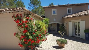 A courtyard with a paved pathway, a building with a tiled roof, and a potted plant. - 2 apartments in a beautiful, quiet property between vineyards and the sea. Large swimming pool (LES ARCS)