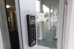 A keypad lock on a door with a sign in the background. - Hiisi Homes Hämeenlinna Asemanranta (Hameenlinna)