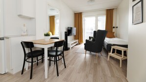 A modern, well-lit room with a dining area, a sofa, a TV, and a bed. - Hiisi Homes Hämeenlinna Asemanranta (Hameenlinna)